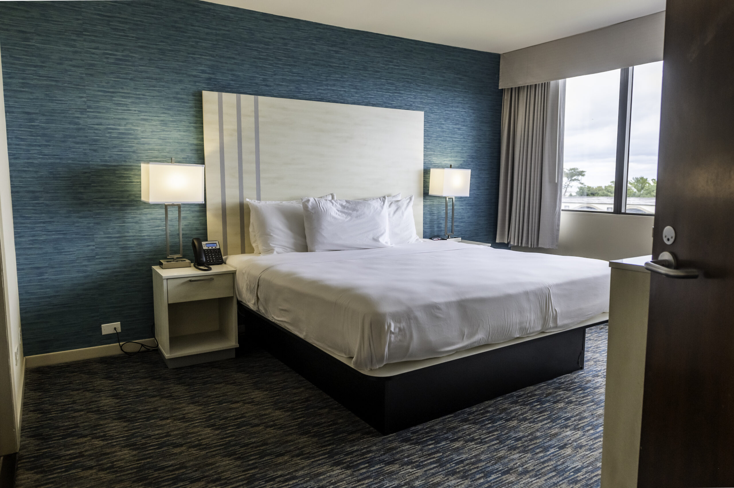 King Bedroom with a large king bed with white bed sheets. The room has a large view of the beach and Lake Michigan.