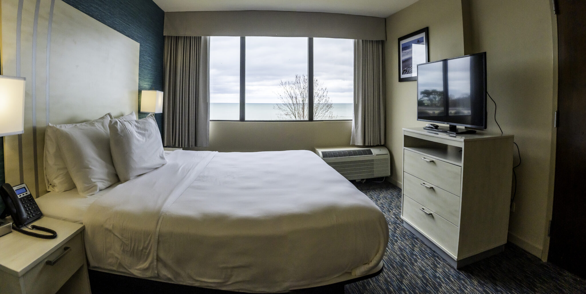 Illinois Beach Hotel Room including a king bed with a television on top of a dresser. The room also includes a beach view of Lake Michigan.